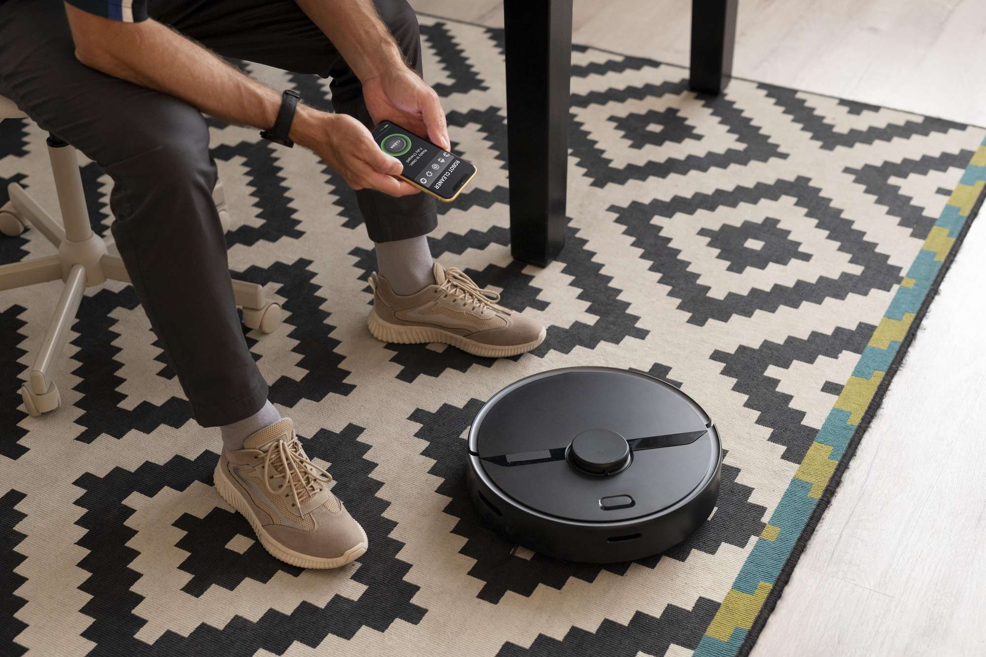 a man controlling a robot vacuum cleaner (can Roomba go over rugs)